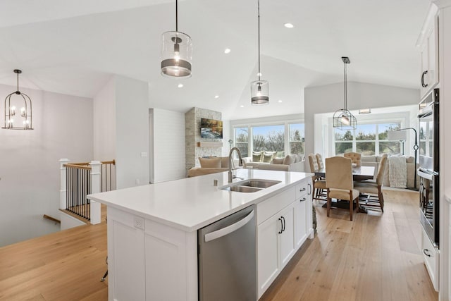 kitchen featuring vaulted ceiling, stainless steel dishwasher, a sink, open floor plan, and a center island with sink