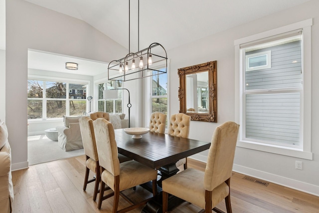 dining space featuring vaulted ceiling, a chandelier, light wood-style flooring, baseboards, and visible vents