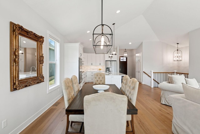 dining space with light wood finished floors, baseboards, recessed lighting, a notable chandelier, and lofted ceiling