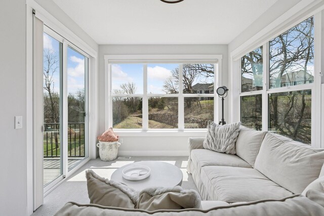 sunroom featuring baseboards, a wealth of natural light, and carpet