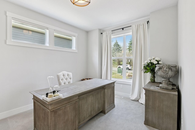 home office with baseboards, a healthy amount of sunlight, visible vents, and light carpet