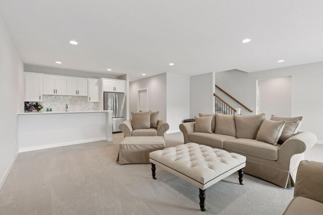 living area featuring light colored carpet, baseboards, stairs, and recessed lighting