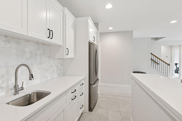 kitchen featuring light countertops, freestanding refrigerator, a sink, and tasteful backsplash