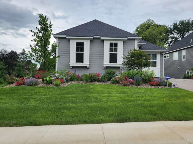 bungalow-style house featuring a shingled roof and a front yard