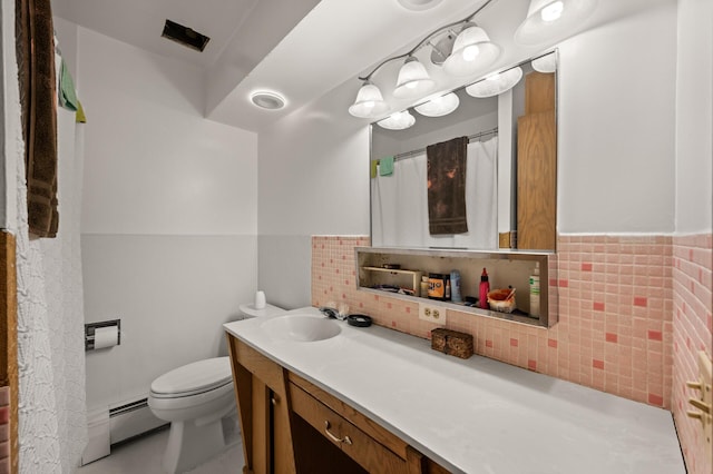 full bath with toilet, a baseboard heating unit, wainscoting, and vanity