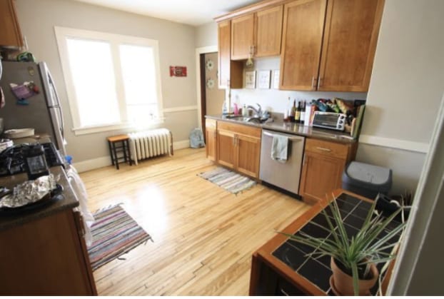 kitchen featuring stainless steel appliances, radiator heating unit, light wood finished floors, a sink, and baseboards
