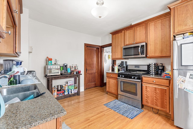 382 Fry St, Saint Paul, MN 55104 - kitchen featuring appliances with stainless steel finishes, light wood-style floors, a sink, and light stone counters