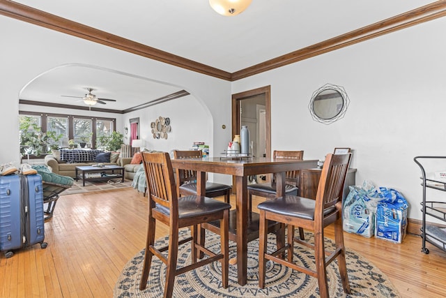 382 Fry St, Saint Paul, MN 55104 - dining room featuring arched walkways, crown molding, light wood finished floors, and ceiling fan