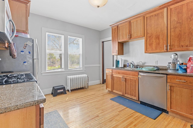 382 Fry St, Saint Paul, MN 55104 - kitchen with radiator heating unit, stainless steel appliances, a sink, light wood-style floors, and brown cabinetry