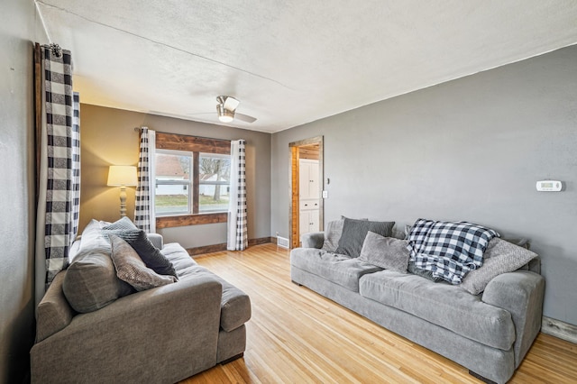 living room with ceiling fan, baseboards, and wood finished floors
