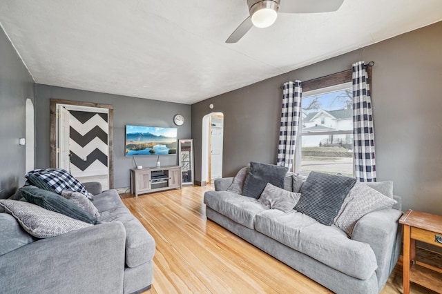 living room featuring ceiling fan, arched walkways, and light wood-style floors