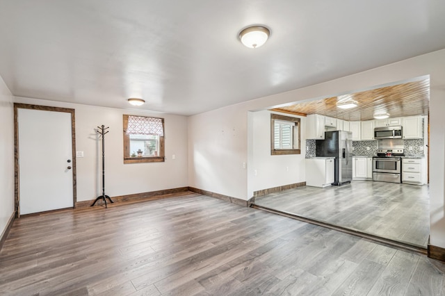 unfurnished living room with baseboards and wood finished floors