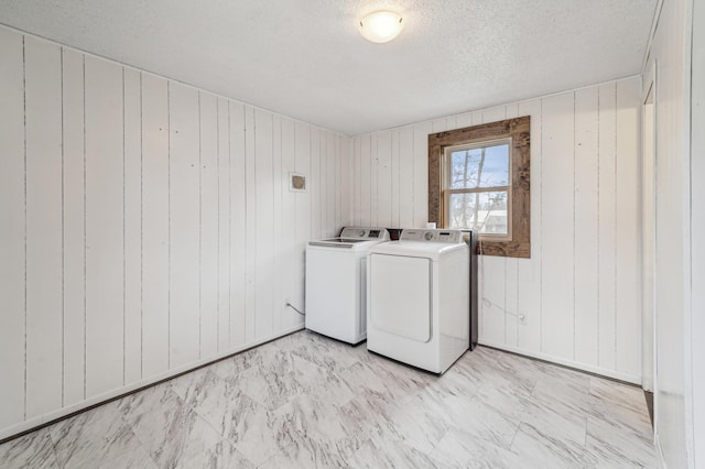 laundry room with wood walls, washing machine and dryer, laundry area, and a textured ceiling