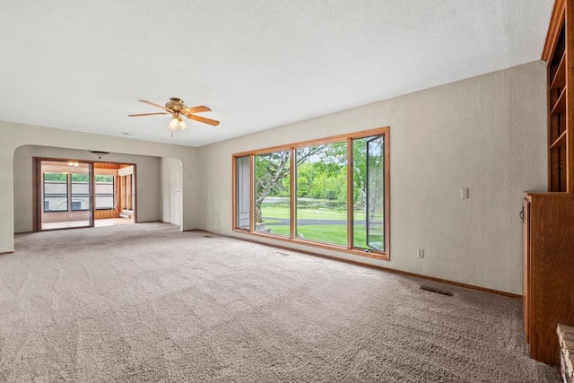 2591 Carver Ave E, Maplewood, MN 55119 - carpeted spare room featuring a textured wall, a ceiling fan, baseboards, and arched walkways
