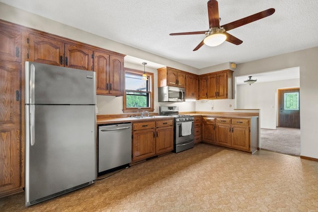 2591 Carver Ave E, Maplewood, MN 55119 - kitchen featuring appliances with stainless steel finishes, a sink, light countertops, a ceiling fan, and brown cabinetry
