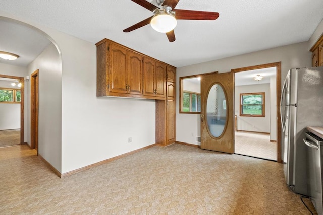 2591 Carver Ave E, Maplewood, MN 55119 - kitchen with appliances with stainless steel finishes, a ceiling fan, brown cabinetry, arched walkways, and baseboards