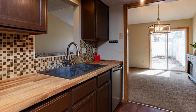 kitchen featuring an inviting chandelier, stainless steel dishwasher, a sink, decorative backsplash, and butcher block countertops