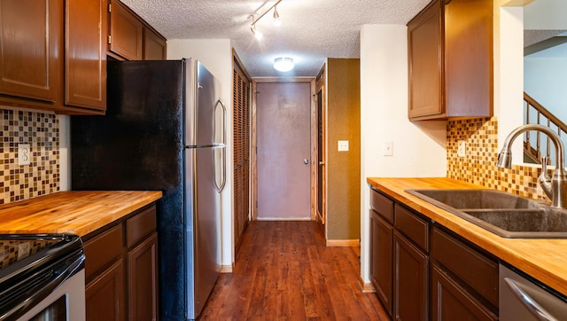 kitchen with dark wood-style floors, stainless steel appliances, a sink, wood counters, and a textured ceiling