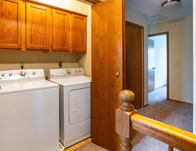 clothes washing area with washing machine and dryer, light colored carpet, and cabinet space