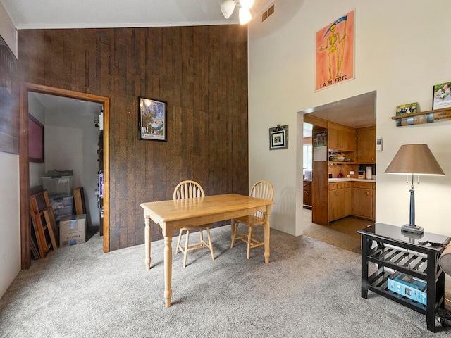 2595 Carver Ave E, Maplewood, MN 55119 - dining area with light colored carpet, a towering ceiling, and wood walls