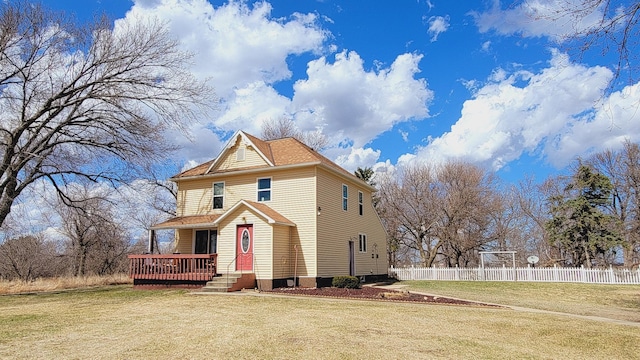 victorian home with a wooden deck, a front yard, and fence