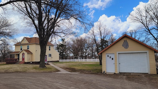 exterior space with a garage, a lawn, fence, an outbuilding, and driveway
