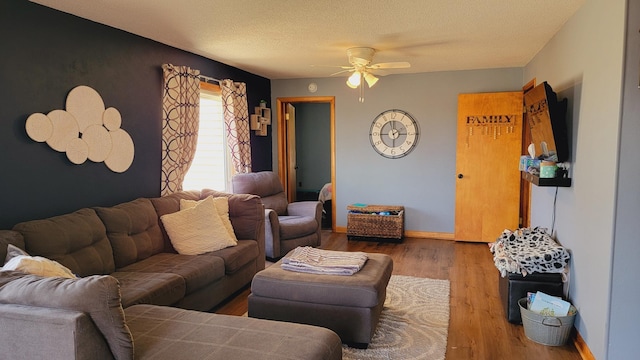 living room featuring ceiling fan, a textured ceiling, wood finished floors, and baseboards