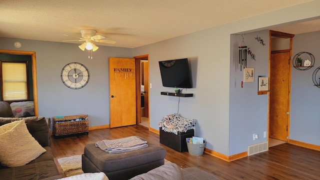 living room featuring visible vents, baseboards, a ceiling fan, and wood finished floors