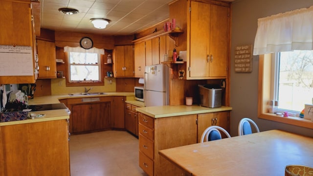 kitchen featuring brown cabinets, a sink, open shelves, and white appliances