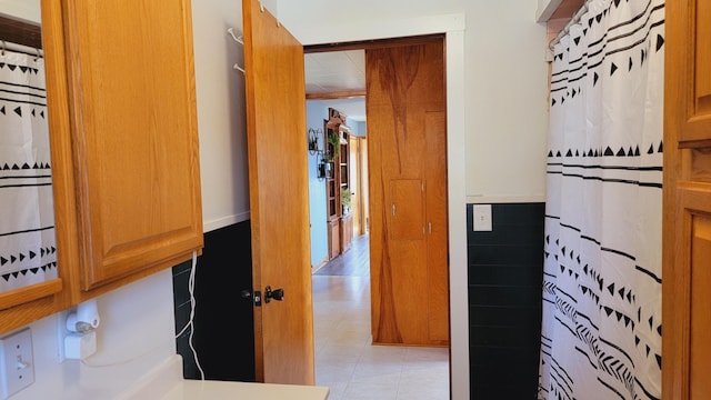 hall featuring tile walls and a wainscoted wall