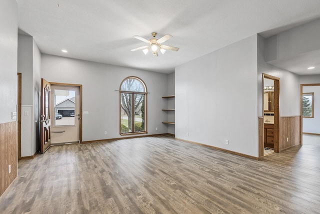 unfurnished living room featuring ceiling fan, baseboards, and wood finished floors