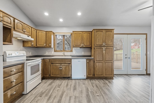 kitchen with light wood-style floors, white appliances, under cabinet range hood, a sink, and brown cabinets
