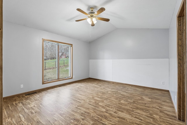 interior space with baseboards, vaulted ceiling, visible vents, ceiling fan, and wood finished floors