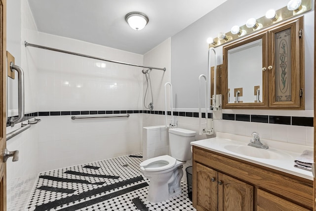 bathroom featuring tile patterned flooring, toilet, tiled shower, and vanity