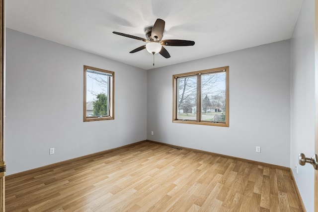 unfurnished room featuring light wood-type flooring, a healthy amount of sunlight, baseboards, and a ceiling fan