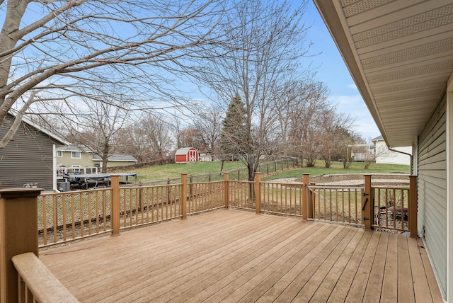 wooden deck featuring a lawn, a storage shed, and an outbuilding