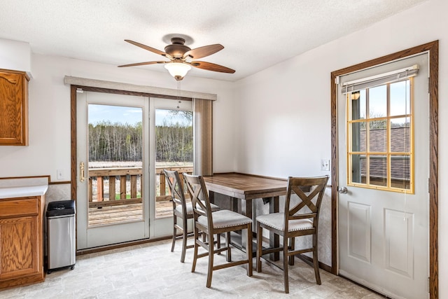 dining space with a healthy amount of sunlight, ceiling fan, and a textured ceiling