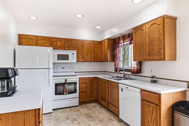 kitchen with a sink, brown cabinets, white appliances, and light countertops
