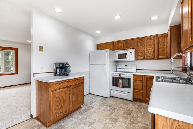 kitchen featuring a sink, recessed lighting, brown cabinets, and white appliances