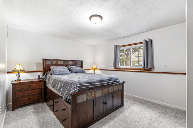 bedroom featuring a textured ceiling, light colored carpet, and a wainscoted wall
