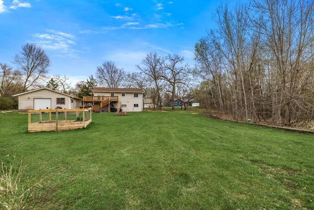 view of yard featuring a garage, a wooden deck, and an outdoor structure