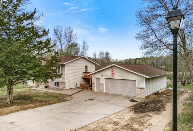 tri-level home with a garage, driveway, roof with shingles, and brick siding