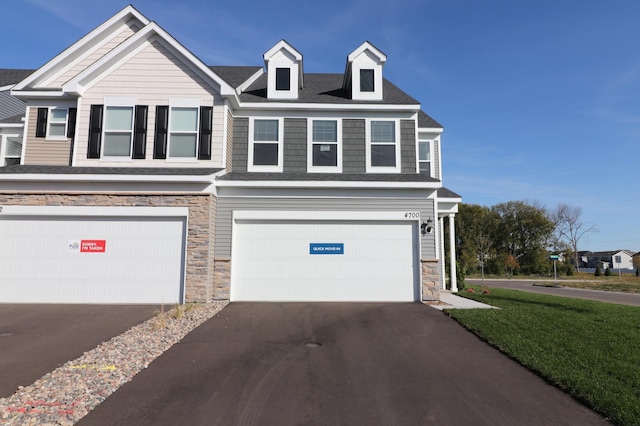 view of front of house with driveway, a garage, stone siding, and a front lawn