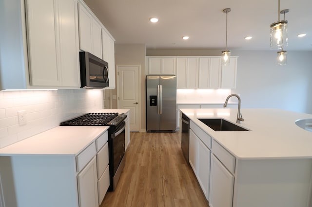 kitchen featuring tasteful backsplash, a sink, light countertops, light wood-type flooring, and stainless steel appliances