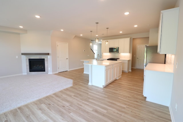kitchen with baseboards, a sink, light countertops, an island with sink, and stainless steel appliances