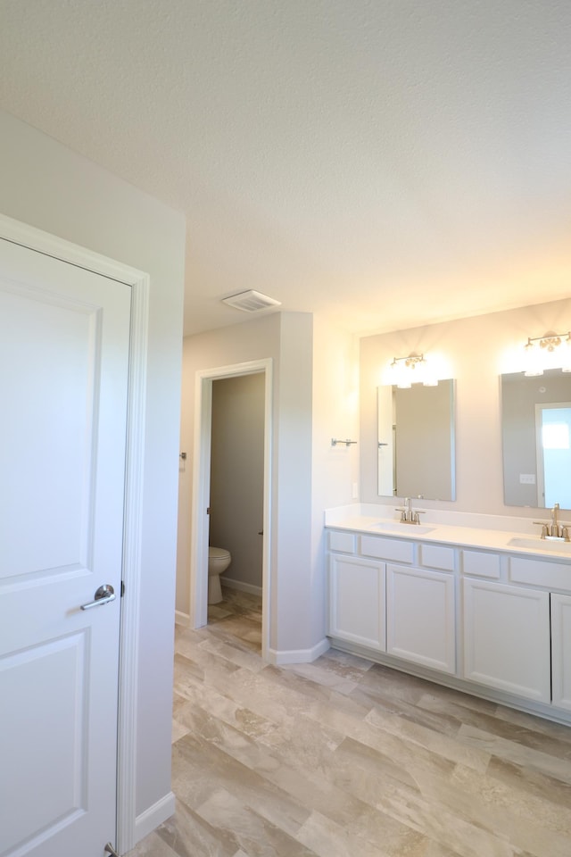full bathroom with double vanity, visible vents, a sink, and toilet