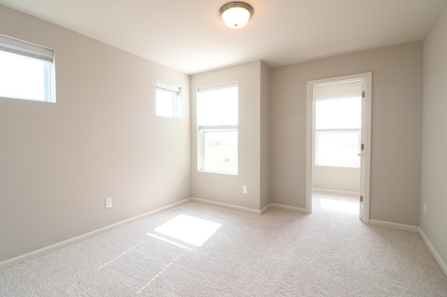empty room featuring light carpet and baseboards