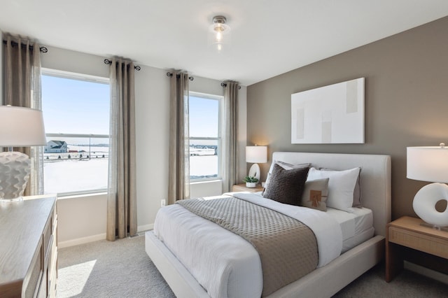 bedroom with a water view, light colored carpet, and baseboards