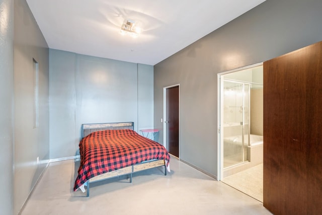bedroom featuring ensuite bath, baseboards, and concrete flooring