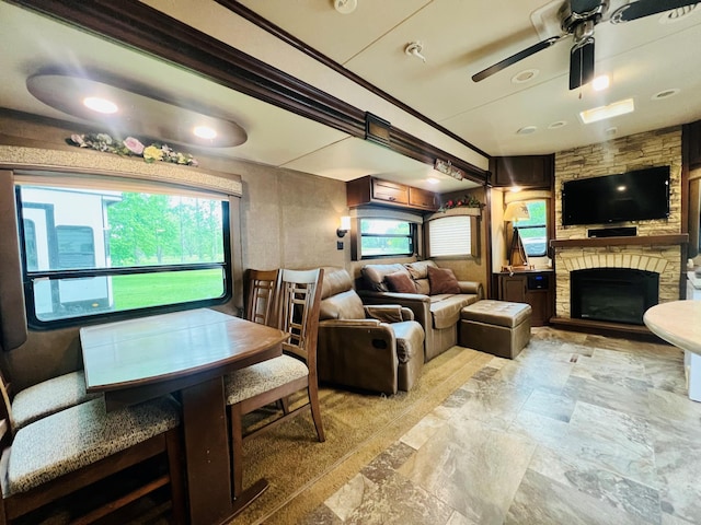 dining space with stone finish flooring, ceiling fan, and a fireplace